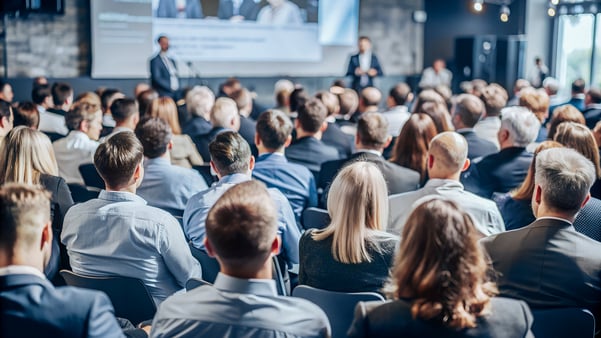 Business professionals watching a speaking seminar at an event