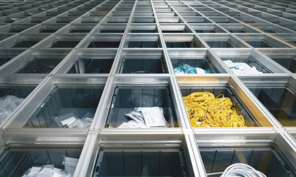 Storage bins in dense grid containing electric wire bundles, small components, and spare parts