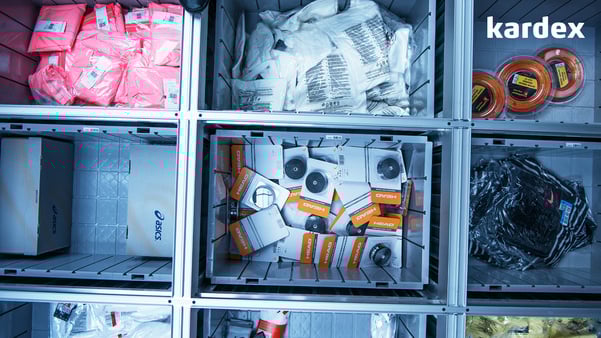 Variety of items stored in gray bins in cube storage system