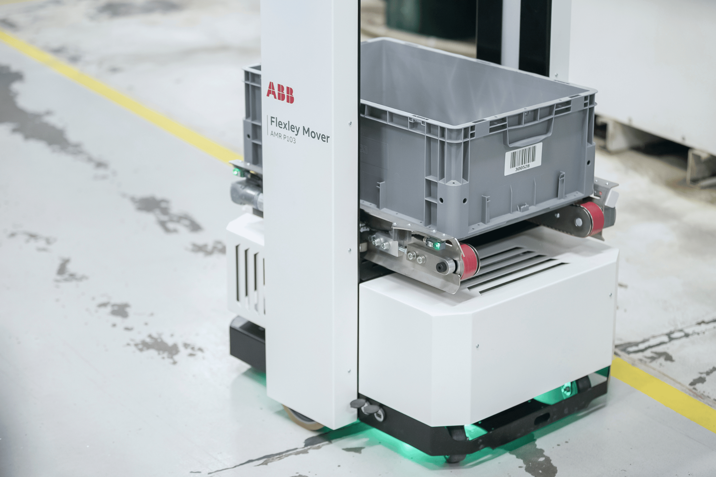 A tote is carried across the warehouse floor by an AMR