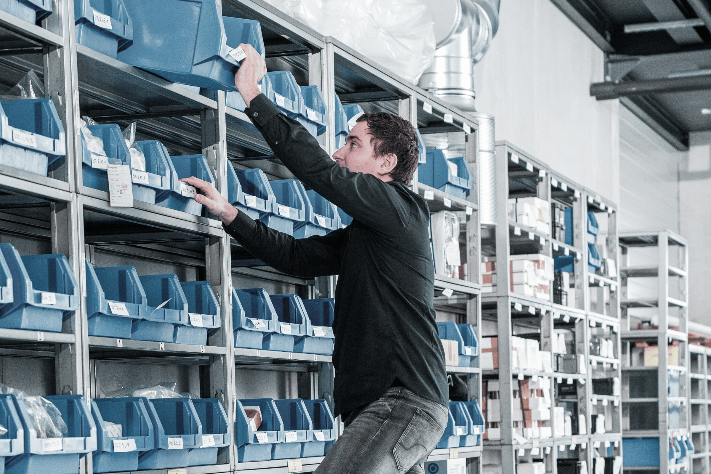 employee on a ladder reaching for overhead bins