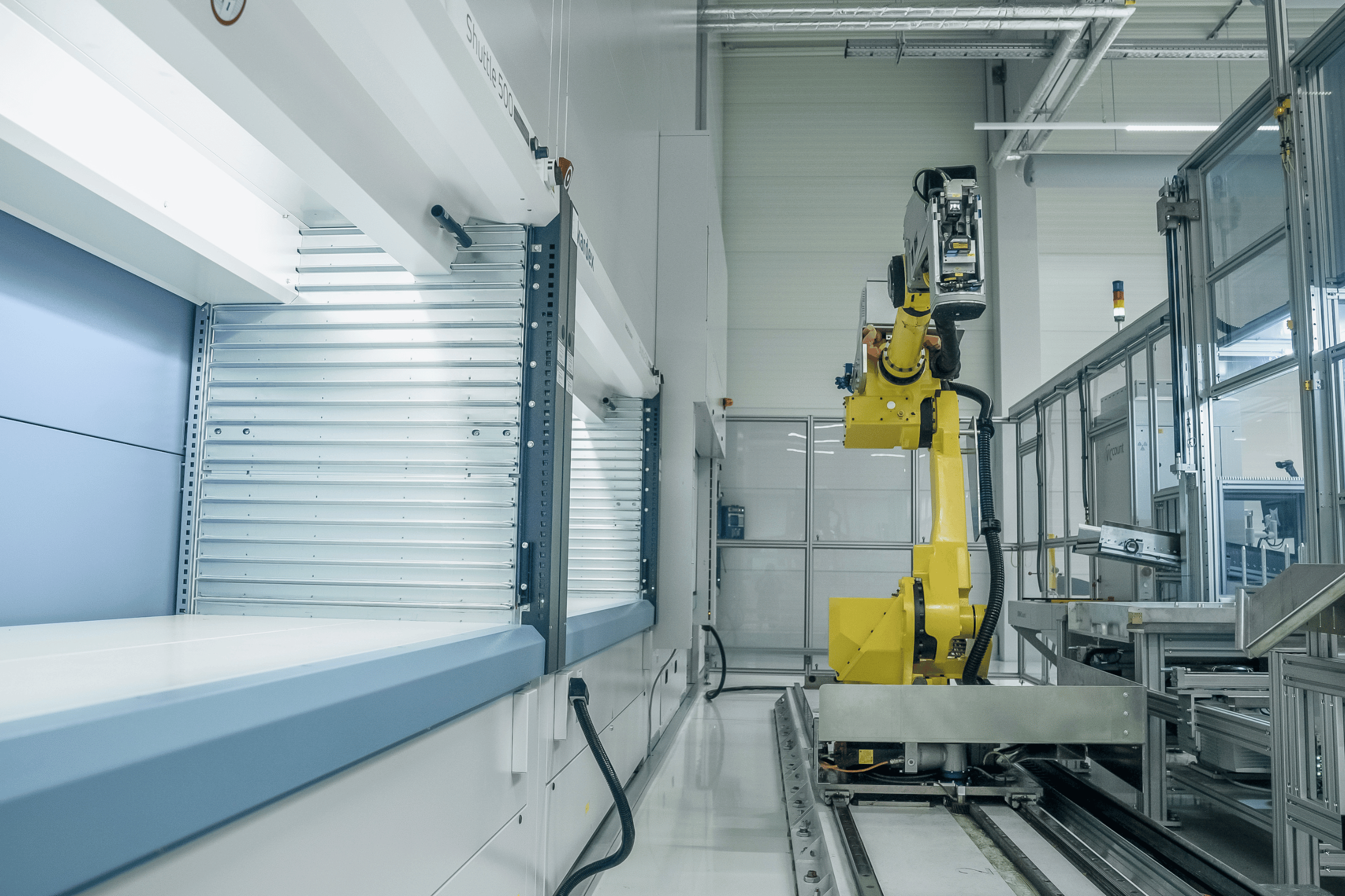 a robotic arm on tracks picks from several vertical lift modules