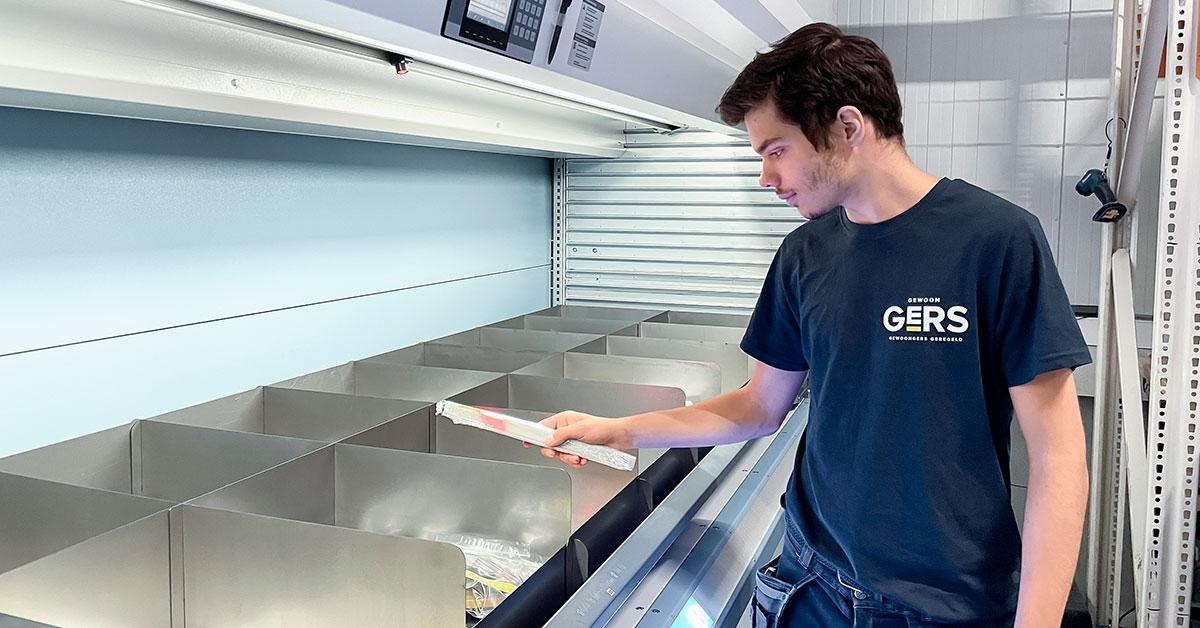 Operador retirando artículos de un módulo de elevación vertical a una altura ergonómica.