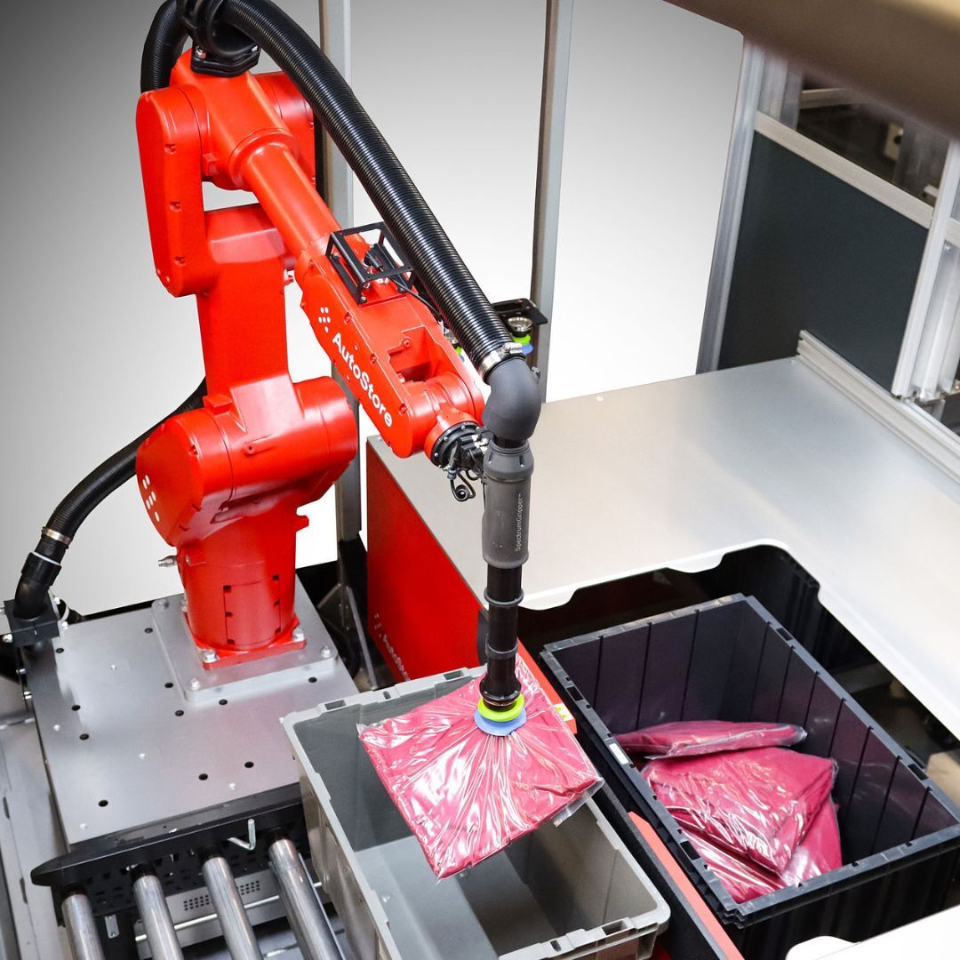 Red robotic arm picking pink t-shirt out of AutoStore solution