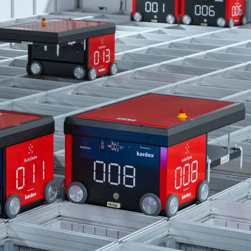 Red square robot with wheels on metal grid Kardex AutoStore R5